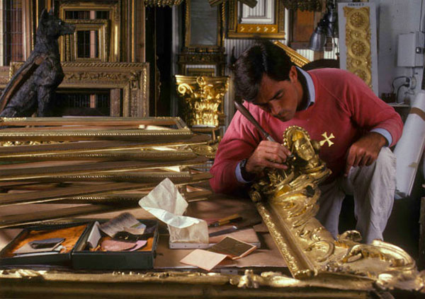 William Adair applying gold leaf to a frame.
